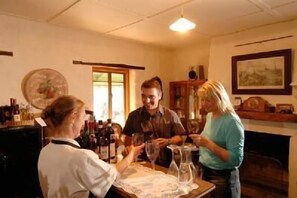 Un comedor con una mesa lista para tres personas, rodeada de botellas y copas, lo que sugiere una reunión o comida.