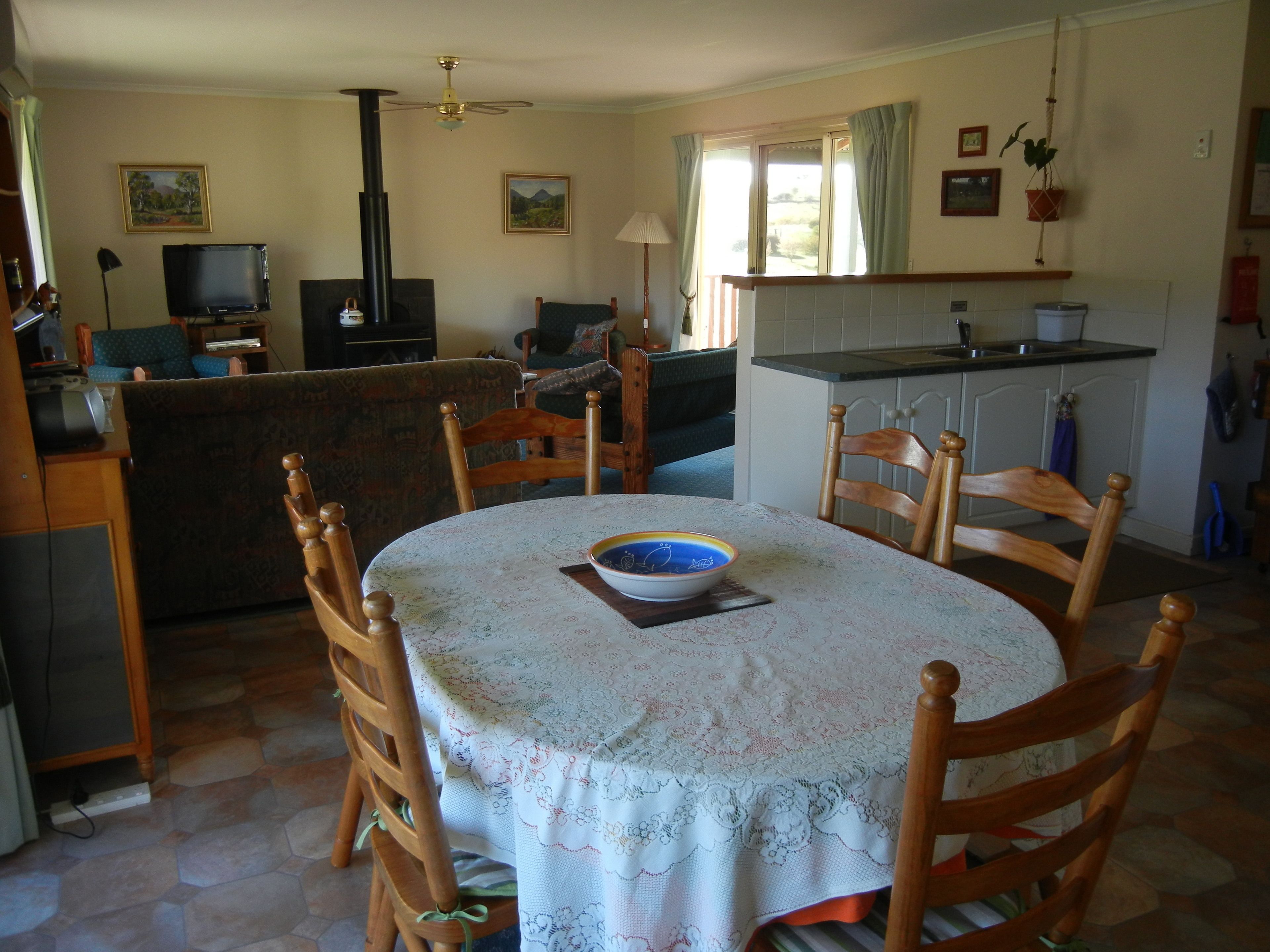 Un comedor con una mesa redonda, sillas, un tazón y un televisor al fondo.