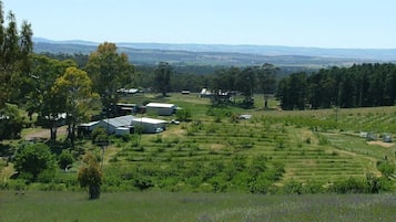 A rural landscape with agricultural fields, a few buildings, and a clear sky.