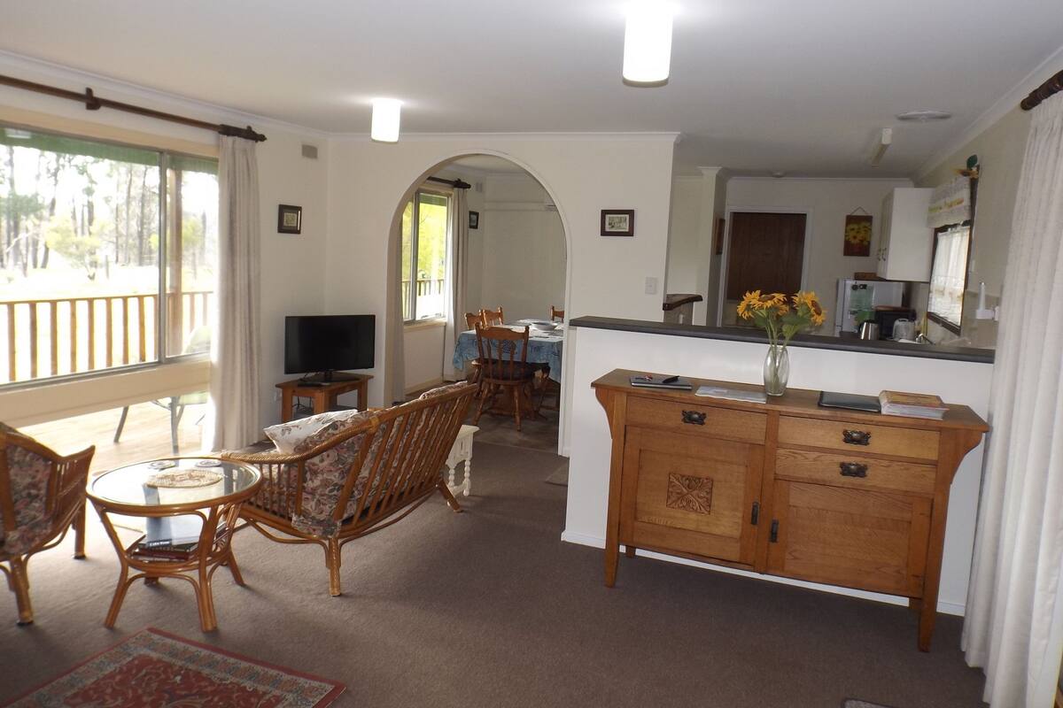A spacious living area with a dining table, chairs, a TV, and a kitchen area with a counter and cabinets.