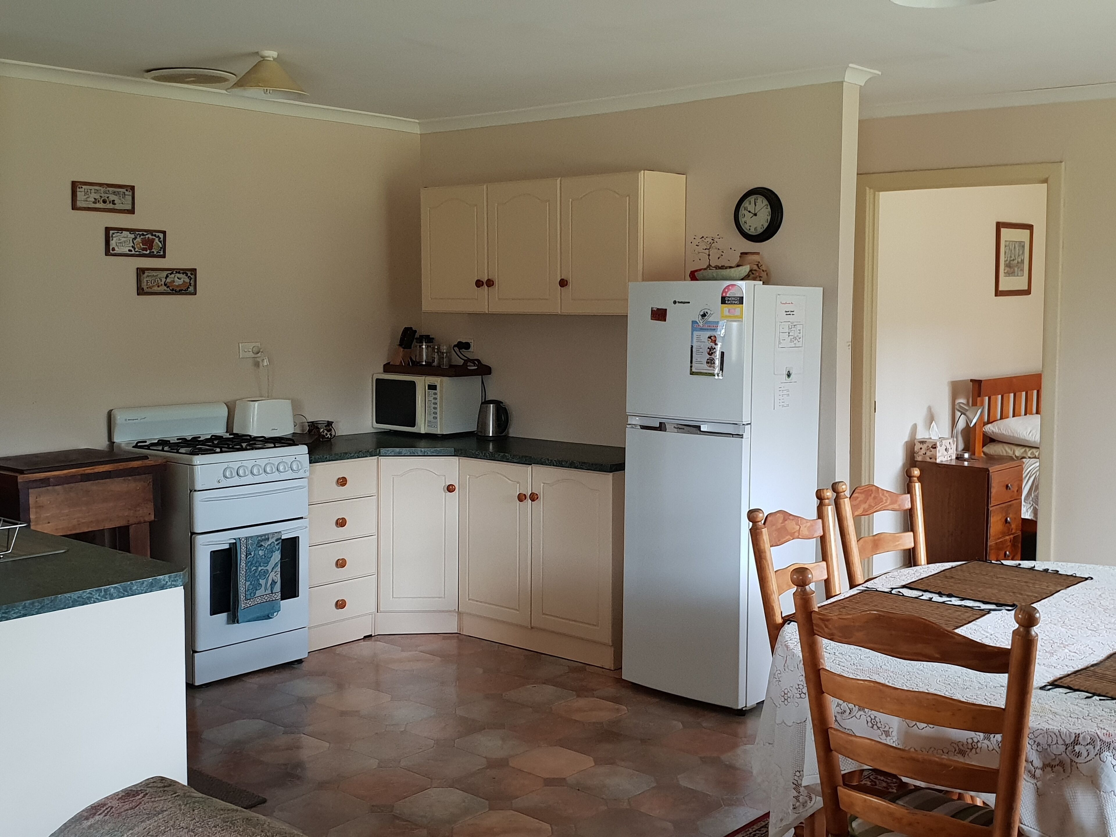 A compact kitchen with a stove, microwave, refrigerator, and wooden cabinets.