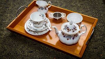 A tray with a teapot, cups, and saucers on a patterned carpet.