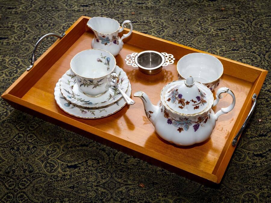 A tray with a teapot, cups, and saucers on a patterned carpet.