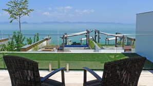 A balcony with wicker chairs, a pool, and a view of the sea.