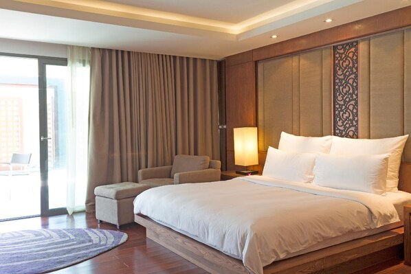 Una habitación de hotel con una cama grande, una silla, una mesita y una lámpara.