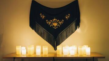 A table with multiple lit candles and a decorative black tapestry with gold embroidery.