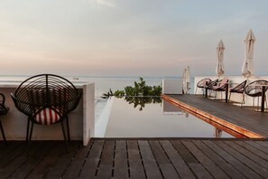 A deck with a wooden floor, chairs, and umbrellas, overlooking a calm body of water. - Memmo Alfama - Design Hotels (Lisbon)