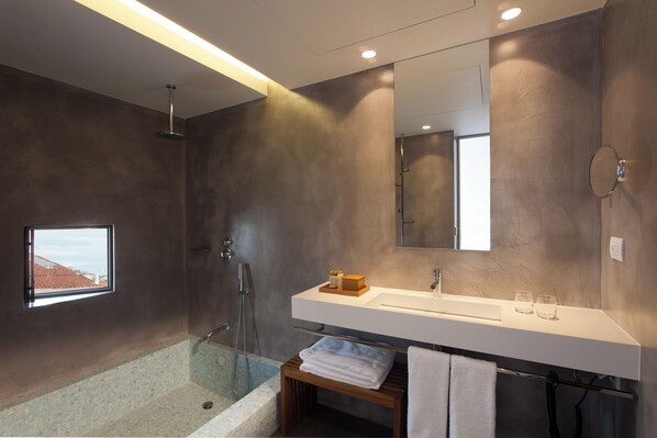 Un baño moderno con un espejo grande, un lavabo blanco y una ducha con mampara de vidrio.