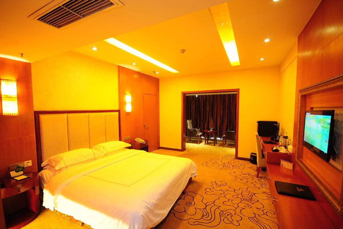 Une chambre d’hôtel avec un grand lit, une télévision, un bureau et une porte donnant sur une salle de bain.