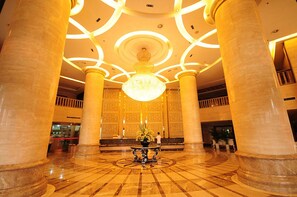 A grand lobby with marble columns, a large chandelier, and a patterned floor. - Baigang International Airport Hotel (Chengdu)
