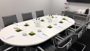 A conference room with a white table, black chairs, and green apples on coasters. - The Resident Soho (London)