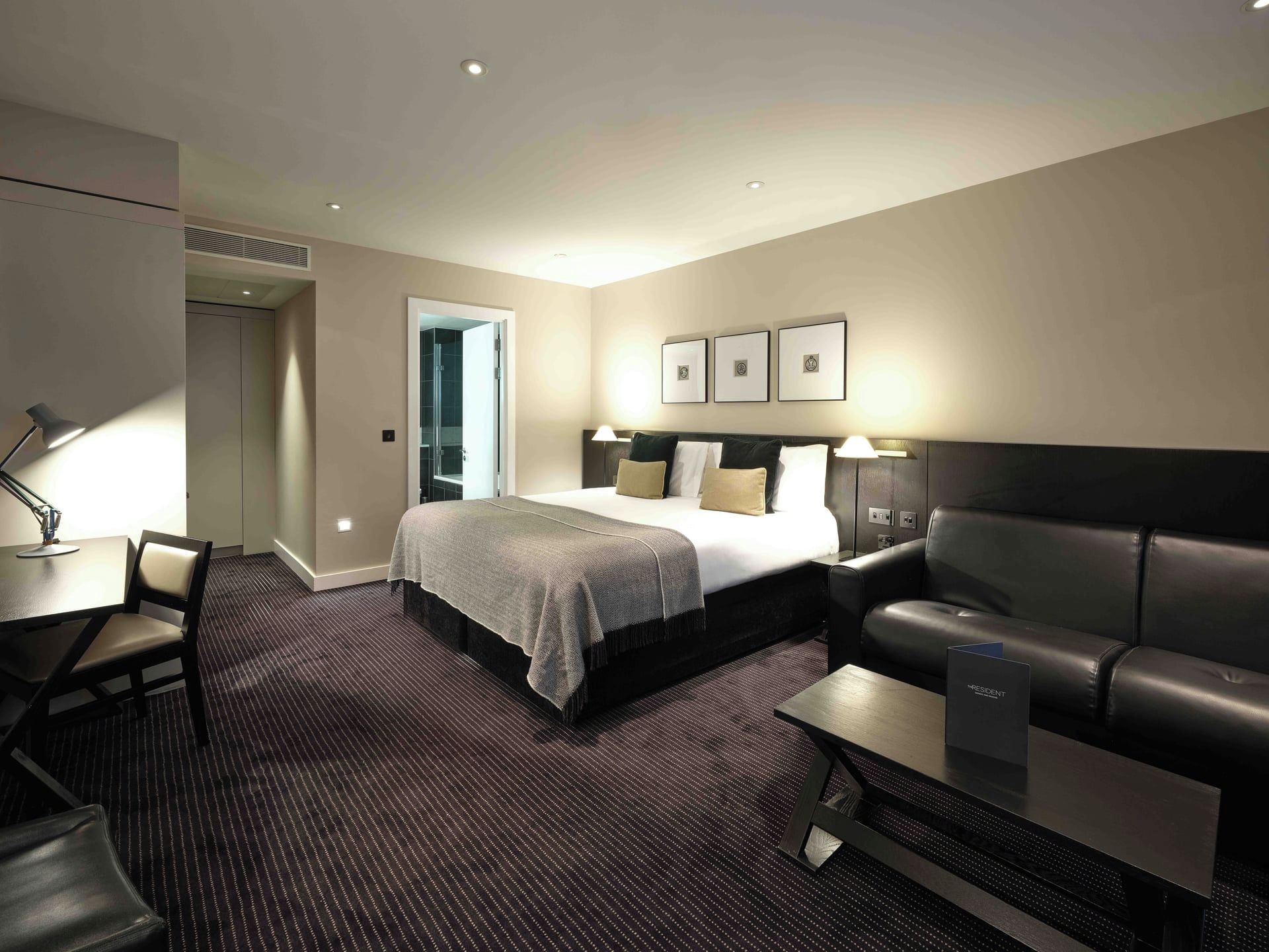 Ein Hotelzimmer mit einem Bett, einem Schreibtisch, einem Stuhl, einer Couch und einem kleinen Tisch.