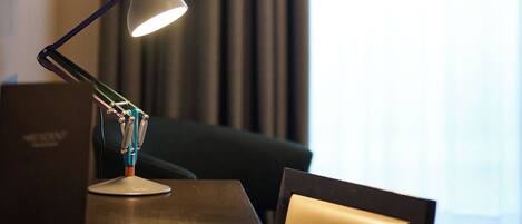 A desk with a desk lamp, a chair, and a window with curtains.