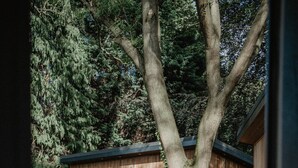 Una cabaña de madera con un balcón y un árbol grande al frente.