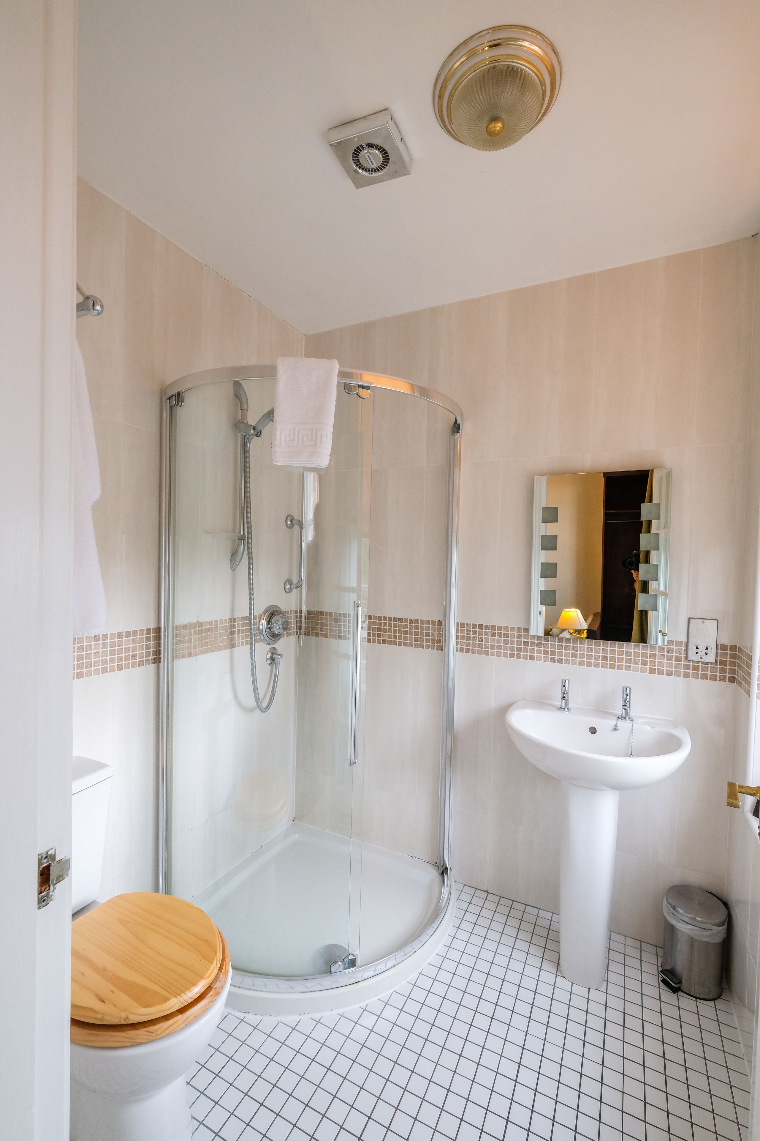 A modern bathroom with a glass-enclosed shower, a white sink, and a wooden toilet.