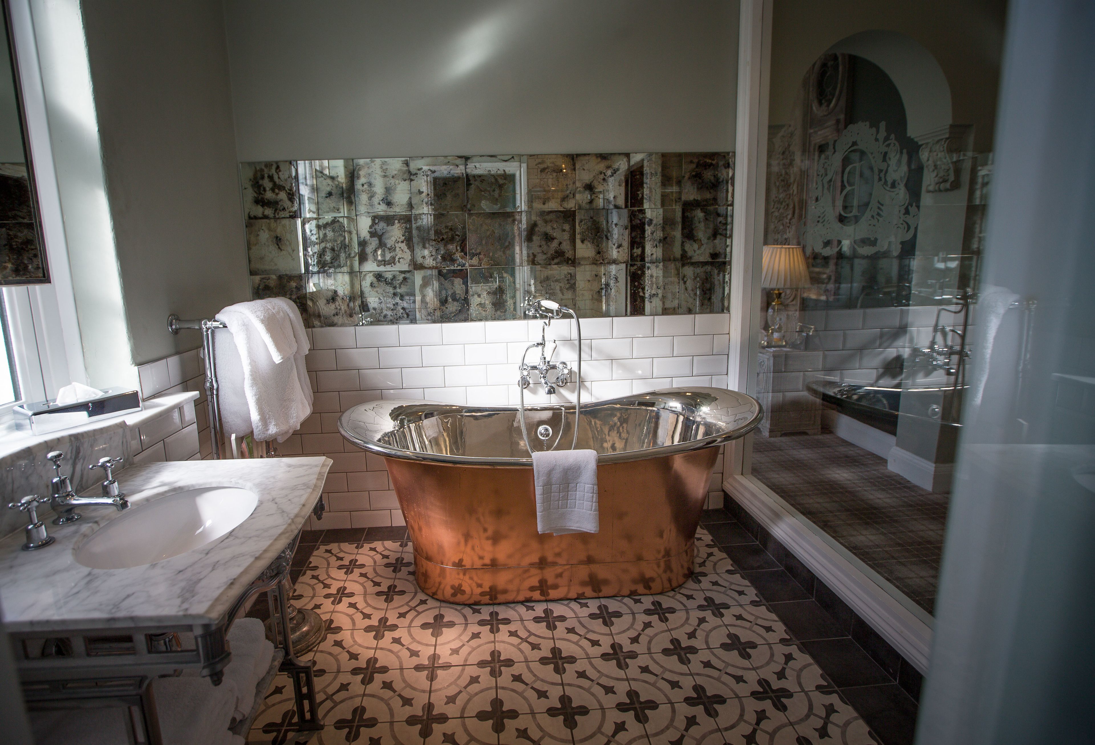 A bathroom with a freestanding bathtub, a sink, and a mirror.