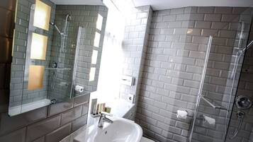 A modern bathroom with a glass shower enclosure, a white sink, and a mirror with integrated lighting.