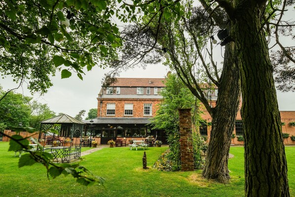 Edificio de ladrillo con patio jardín y zona de estar al aire libre.