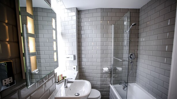 A modern bathroom with a glass shower enclosure, a sink, and a toilet. - Bowburn Hall Hotel (Durham)