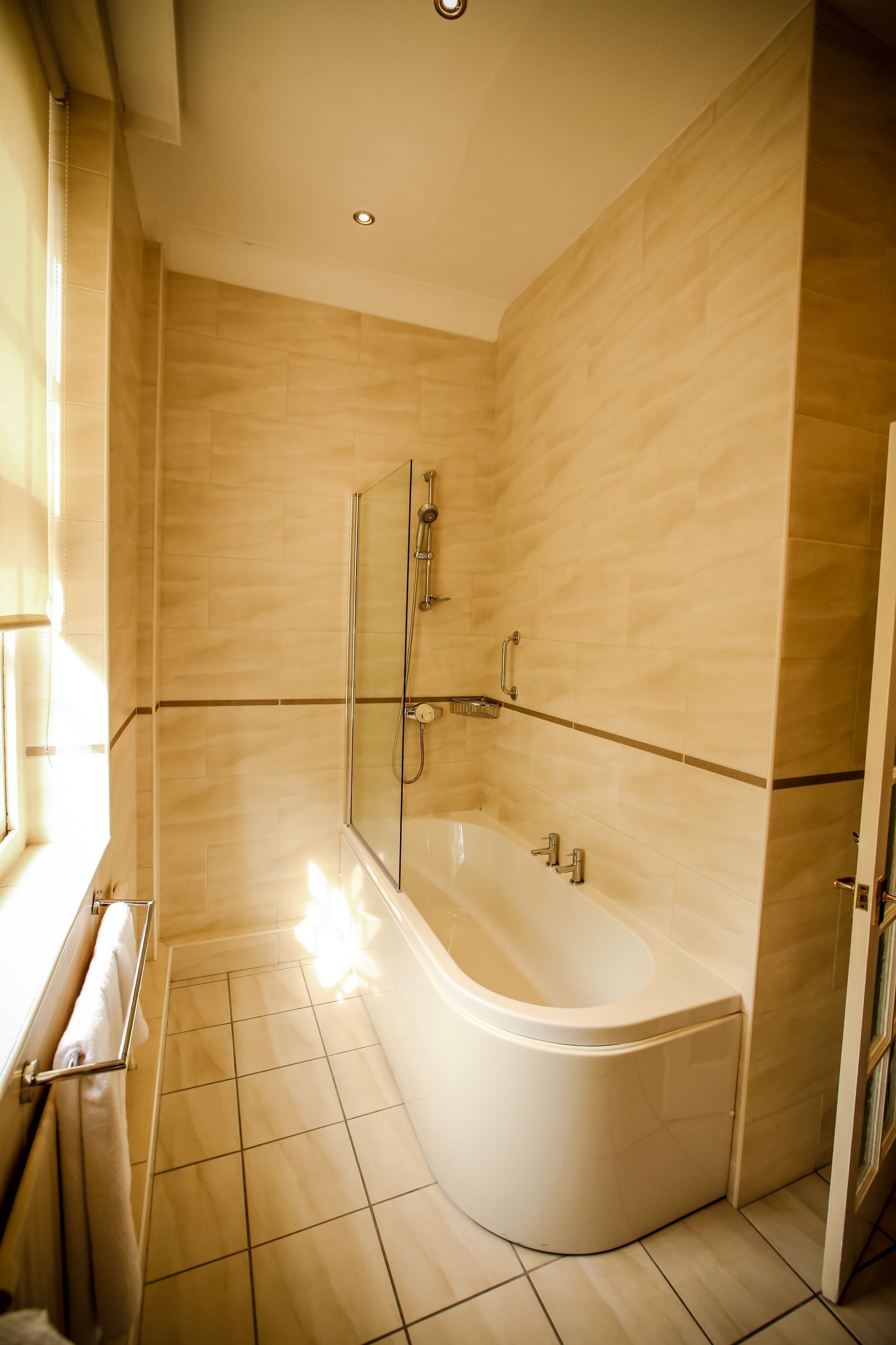 Un baño moderno con una bañera independiente, cabina de ducha de vidrio y piso cubierto de azulejos.