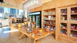 A modern kitchen area with a wooden counter, a refrigerator, and various food items. - Aloft by Marriott Tulsa Downtown (Tulsa)
