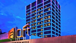 A high-rise hotel building with a modern design, featuring a prominent 'aloft' sign and multiple illuminated windows. - Aloft by Marriott Tulsa Downtown (Tulsa)