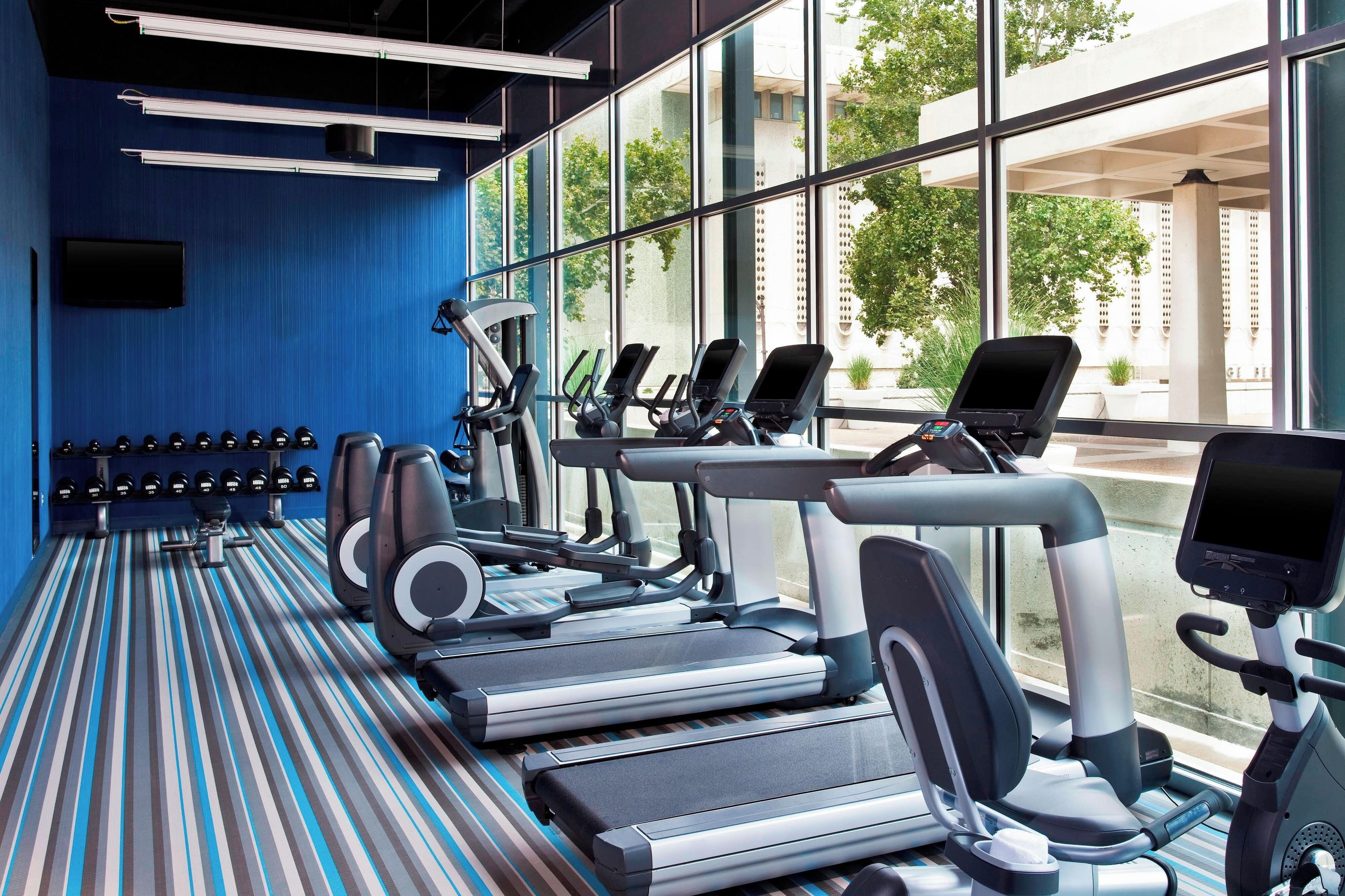 Un gimnasio con cintas de correr, máquinas elípticas y bancos de pesas.