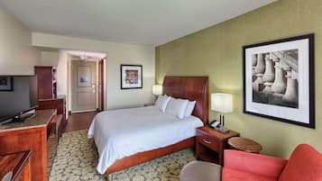 A hotel room with a bed, desk, chair, and a framed picture on the wall.