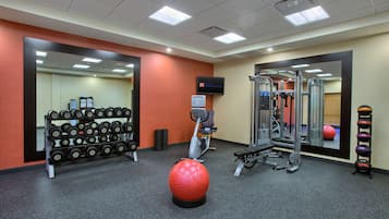 A gym with exercise equipment, a mirror, and a television screen.