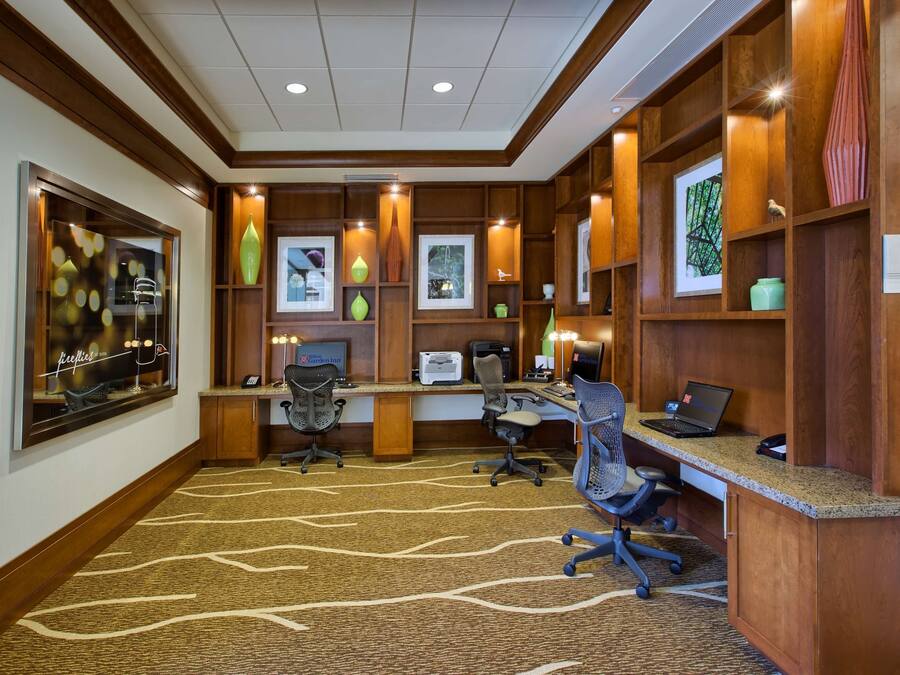 A business center with wooden paneling, multiple workstations, and framed artwork on the walls.