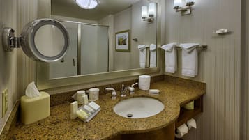 Une salle de bain dotée d’un lavabo avec un plan de travail en granit, d’un grand miroir et d’un porte-serviettes muni de plusieurs serviettes.