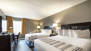 Habitación de hotel con dos camas, un escritorio y una silla.
