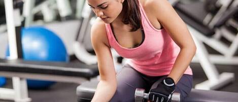 A person exercising with dumbbells in a gym setting.