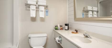 A modern bathroom with a toilet, sink, and bathtub. There are towels and toiletries on the counter.
