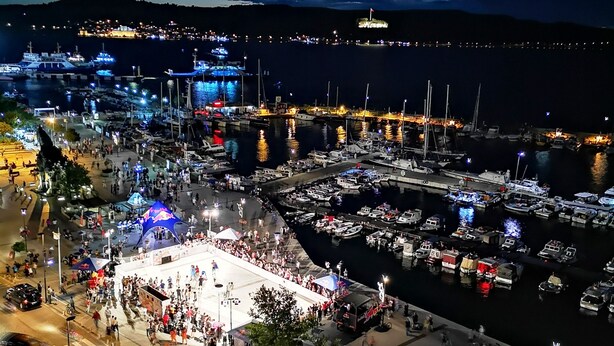 A marina with boats docked, a crowd of people, and a Red Bull tent. - Akol Hotel (Çanakkale)