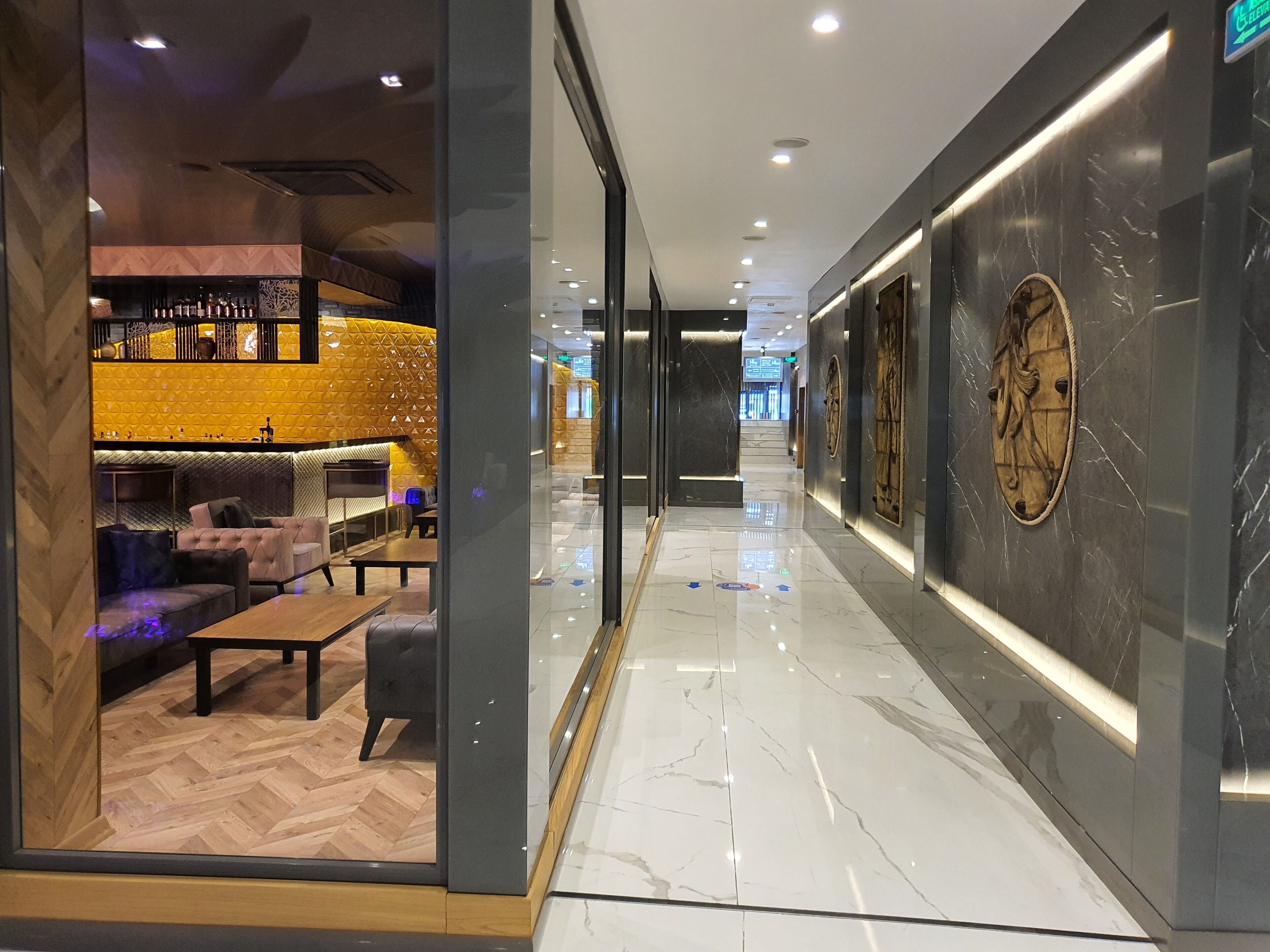 A modern hotel lobby with a bar area, seating, and a marble floor.