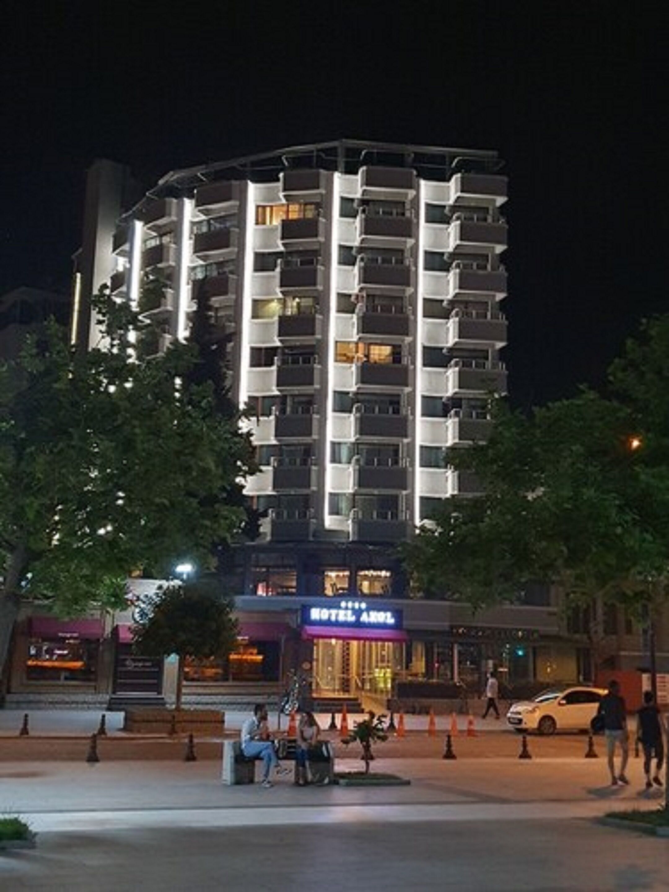 A multi-story hotel with balconies, a visible entrance, and a well-lit facade.