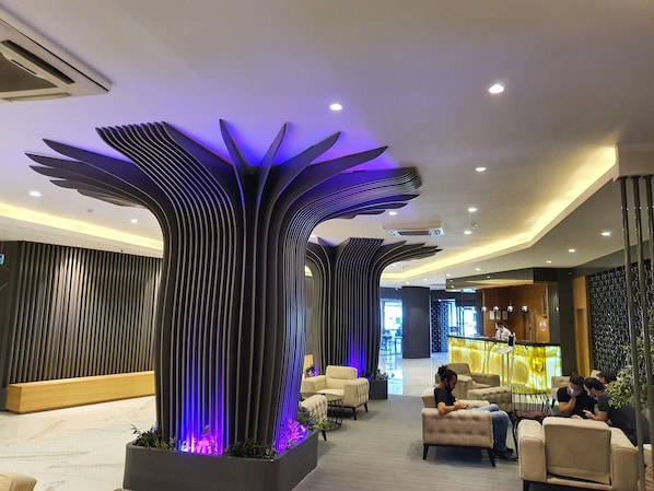 A modern lobby with a unique ceiling design, seating areas, and a reception desk.