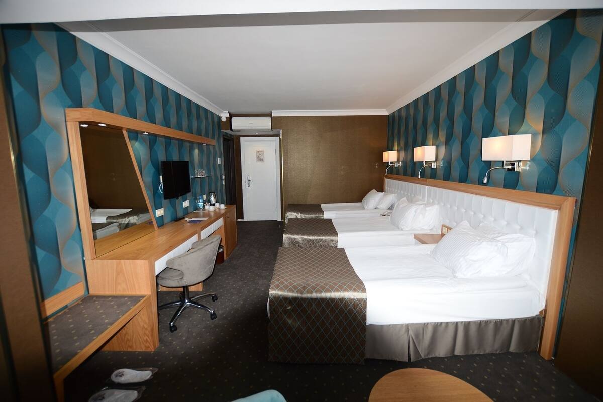 Una habitación de hotel con escritorio, dos camas, espejo y televisor.