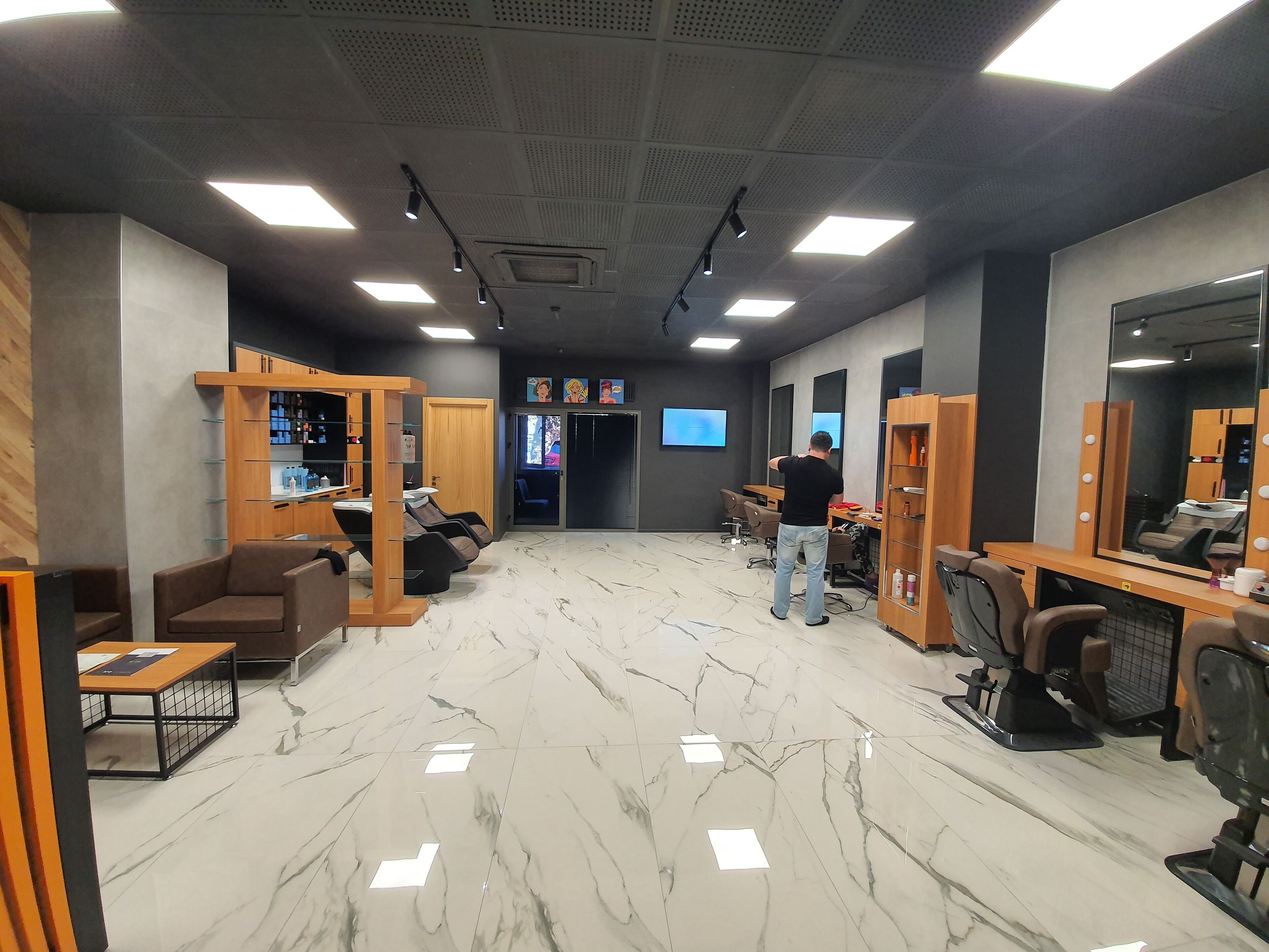 A modern salon with marble floors, wooden furniture, and multiple mirrors.