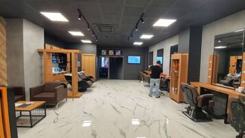 A modern salon with marble floors, wooden furniture, and multiple mirrors.