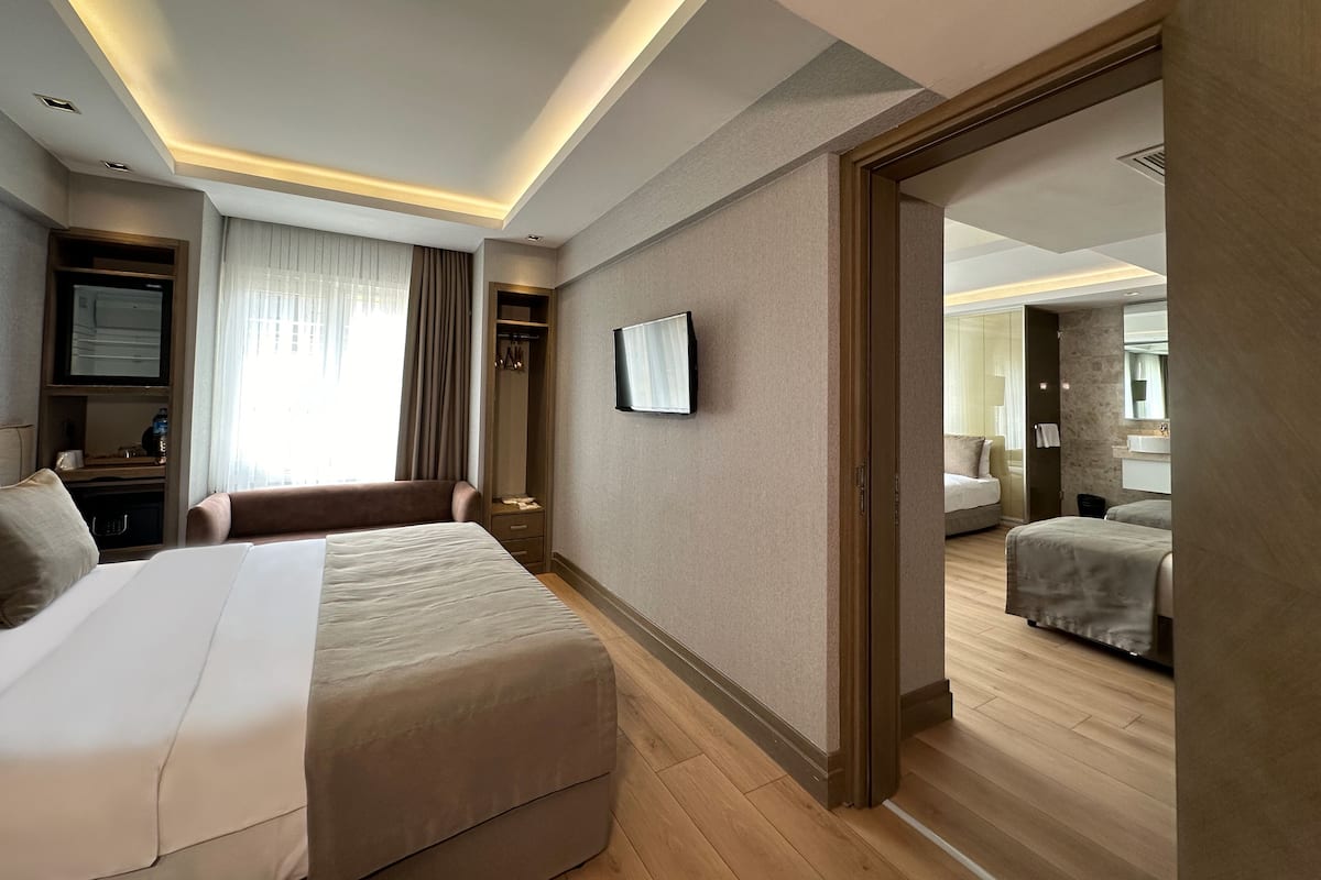A hotel room with a large bed, a wardrobe, a television, and a bathroom visible through an open door.