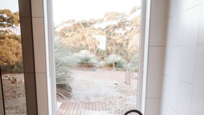 A bathtub with a view of a garden through a large window.