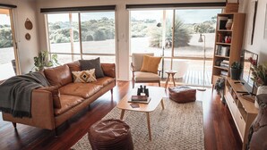 A spacious living room with a leather sofa, a small coffee table, and a bookshelf.