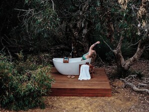 A bathtub on a wooden platform surrounded by dense foliage. - Ecopia Retreat (Seddon)