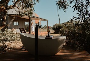 A modern house with a large outdoor seating area featuring a unique boat-shaped table, a wine bottle, and a glass. - Ecopia Retreat (Seddon)