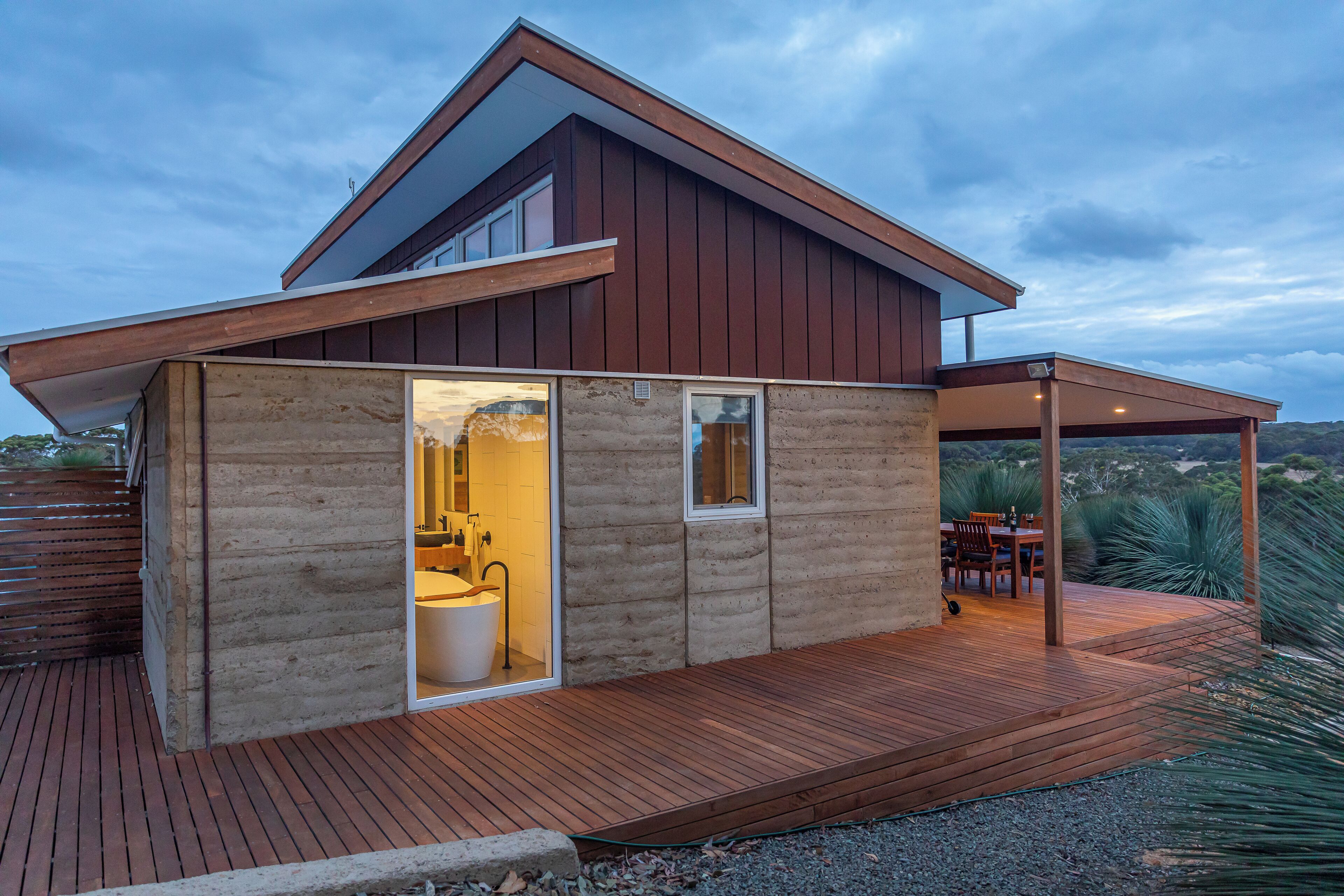 A modern house with a wooden deck, a bathroom with a large window, and a patio area.