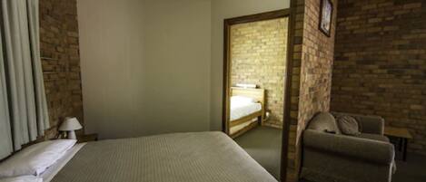 Une chambre d’hôtel avec un grand lit, une chaise, une lampe et un mur en briques.