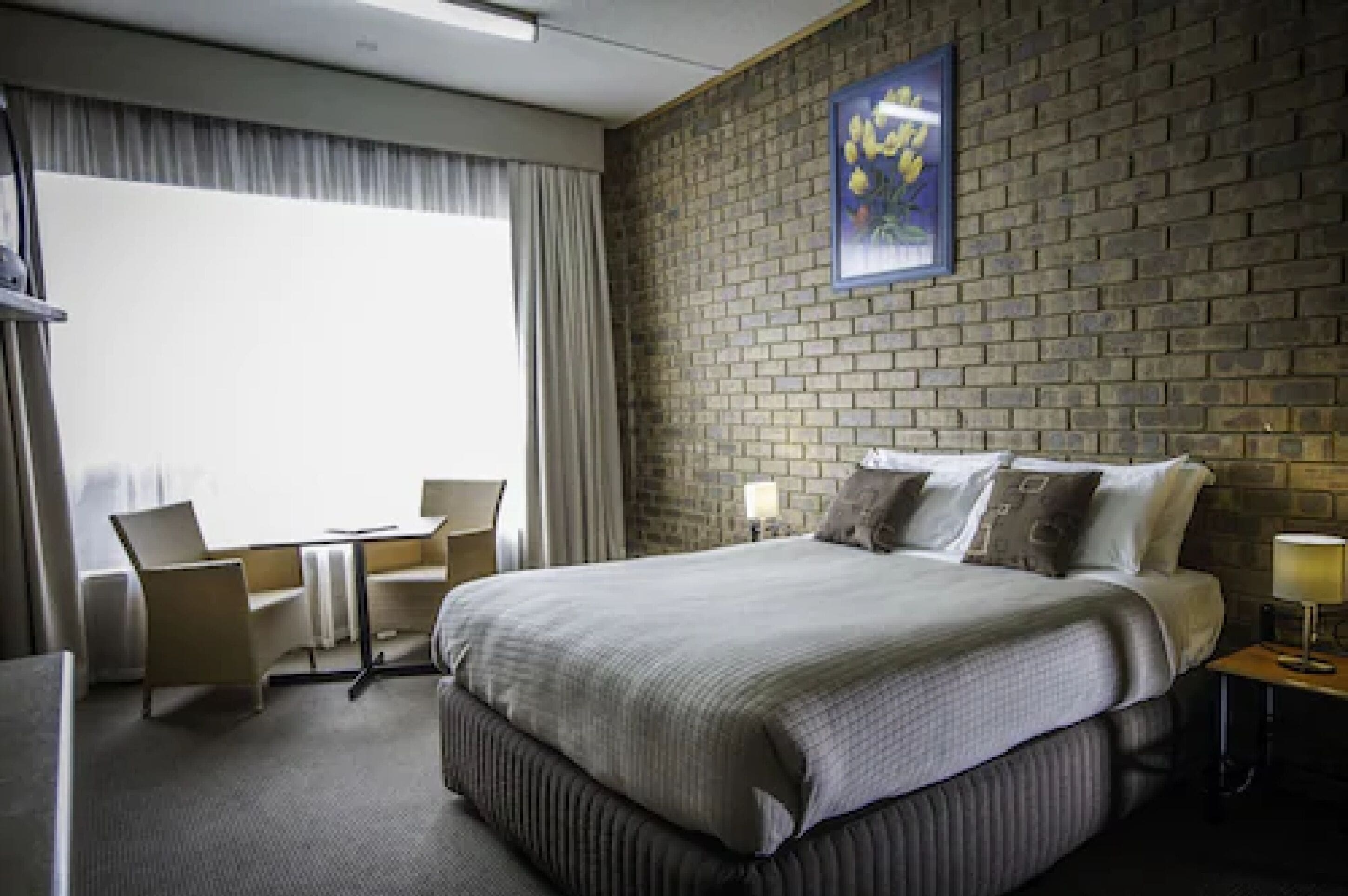 A hotel room with a large bed, a desk, and a chair.