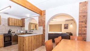 A modern kitchen with wooden cabinets, a central island, and a dining area with a wooden table and chairs. - Mannum Motel (Mannum)